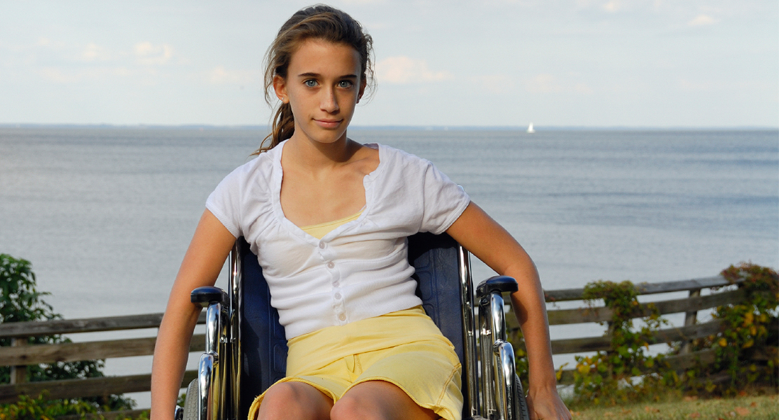 Young girl in a wheelchair in front of the ocean